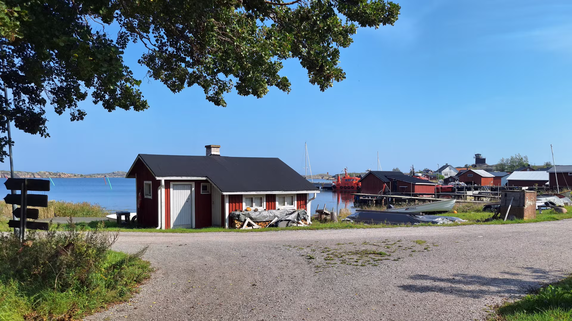 Vägskäl i Utö by – korsning mellan byvägen och Enskärsvägen med röda sjöbodar i skärgårdslandskapet.